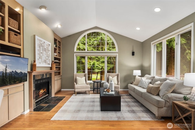 living room featuring a tile fireplace, a wealth of natural light, lofted ceiling, and wood finished floors