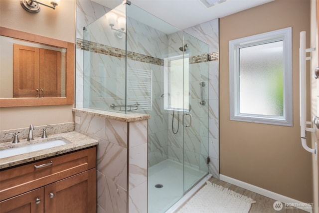 full bath featuring a marble finish shower, vanity, and wood finished floors