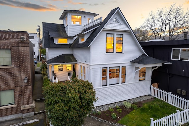 view of front of home with a shingled roof and fence