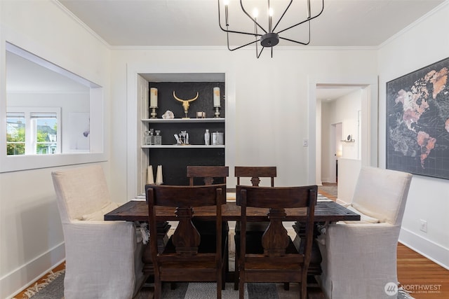 dining area with a notable chandelier, built in shelves, baseboards, wood finished floors, and ornamental molding