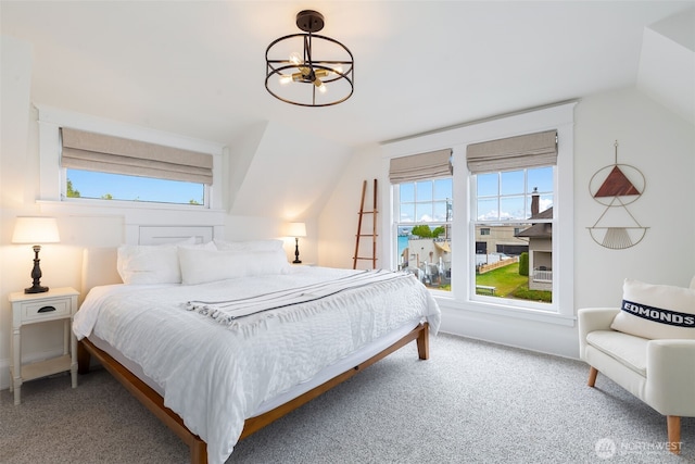 carpeted bedroom with vaulted ceiling, a notable chandelier, and multiple windows