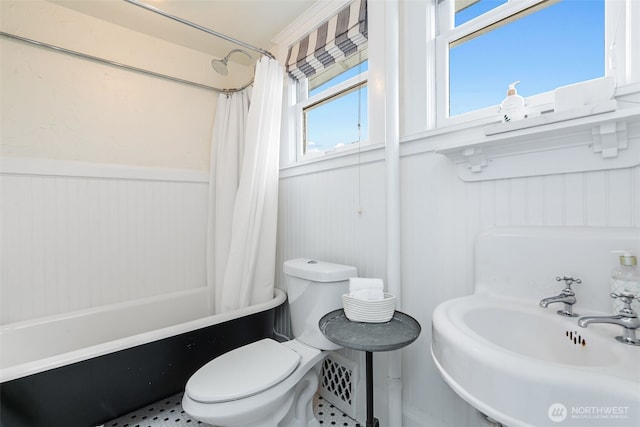 bathroom with shower / tub combo, a sink, wainscoting, and toilet