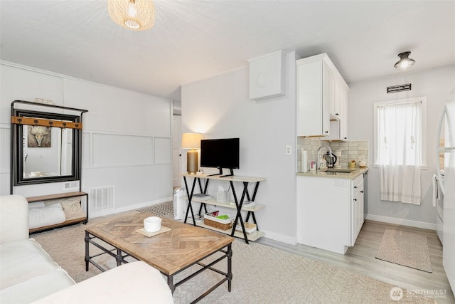 living room featuring baseboards, visible vents, and light wood-type flooring