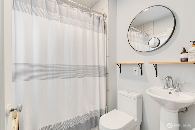 bathroom featuring a sink, a shower with curtain, and toilet