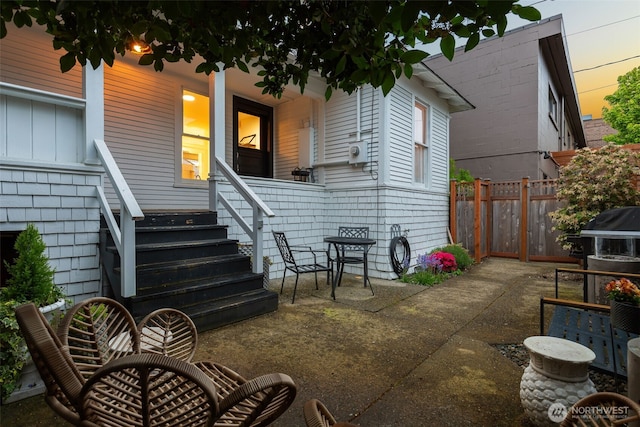 back of property at dusk with fence and covered porch