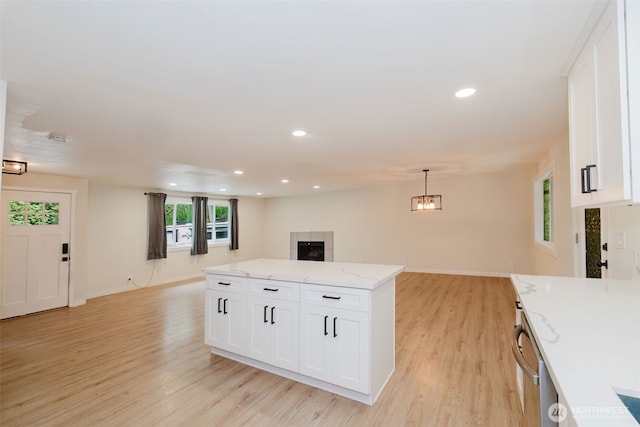 kitchen featuring white cabinets, open floor plan, light stone countertops, and light wood-style floors