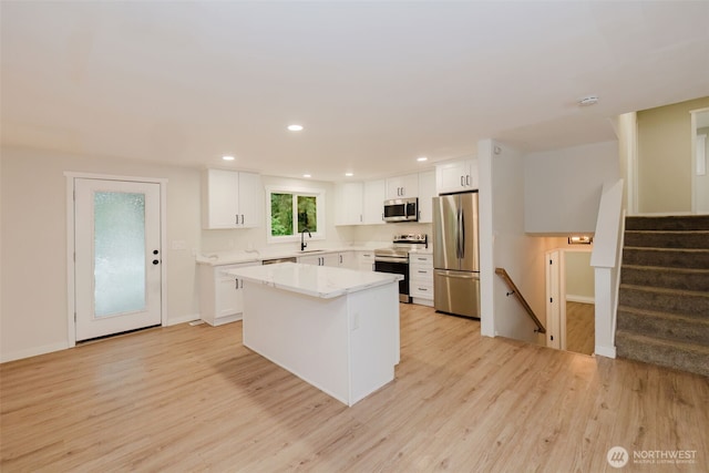 kitchen featuring light wood-style floors, a sink, white cabinetry, and appliances with stainless steel finishes