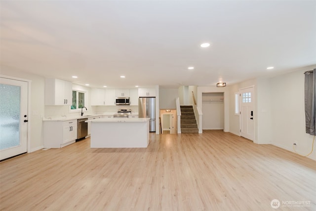kitchen with appliances with stainless steel finishes, light countertops, white cabinets, light wood-style floors, and recessed lighting