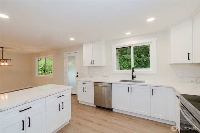 kitchen featuring appliances with stainless steel finishes, a sink, light stone counters, light wood-style floors, and white cabinetry