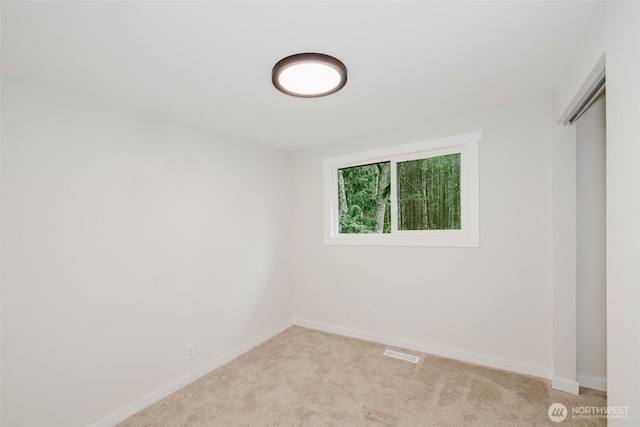 spare room featuring baseboards, visible vents, and light carpet