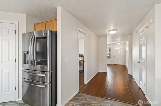 kitchen featuring light brown cabinetry, stainless steel fridge with ice dispenser, a textured ceiling, baseboards, and dark wood-style floors