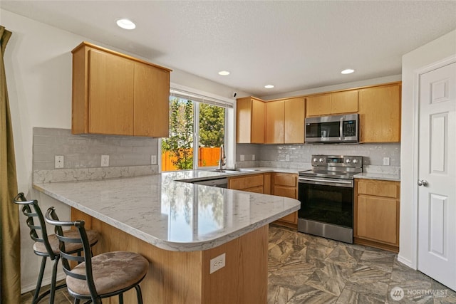kitchen with tasteful backsplash, a sink, a peninsula, a breakfast bar, and stainless steel appliances
