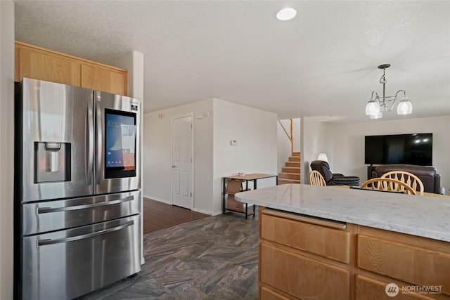 kitchen featuring stainless steel refrigerator with ice dispenser, decorative light fixtures, light stone counters, a chandelier, and open floor plan