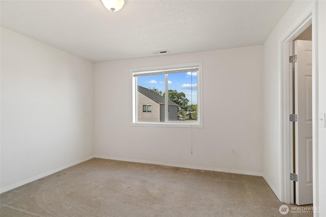 empty room with baseboards, light colored carpet, and visible vents