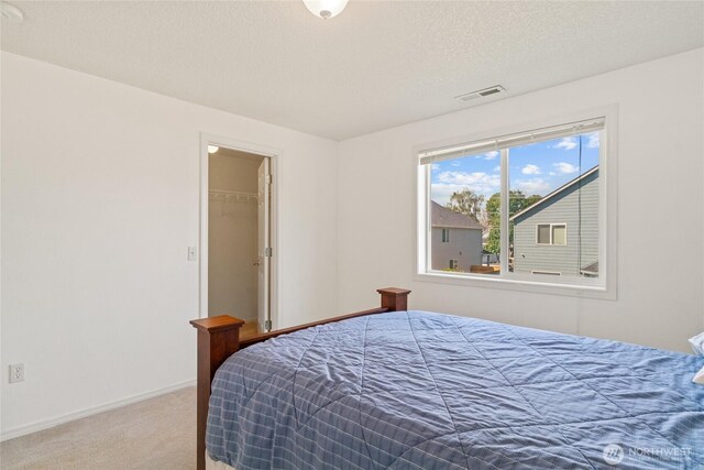 carpeted bedroom with baseboards, a spacious closet, and visible vents