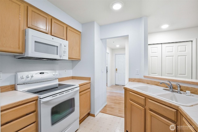 kitchen featuring a sink, white appliances, tile countertops, recessed lighting, and light floors