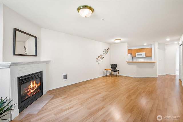 unfurnished living room featuring a fireplace with flush hearth, recessed lighting, light wood finished floors, and visible vents