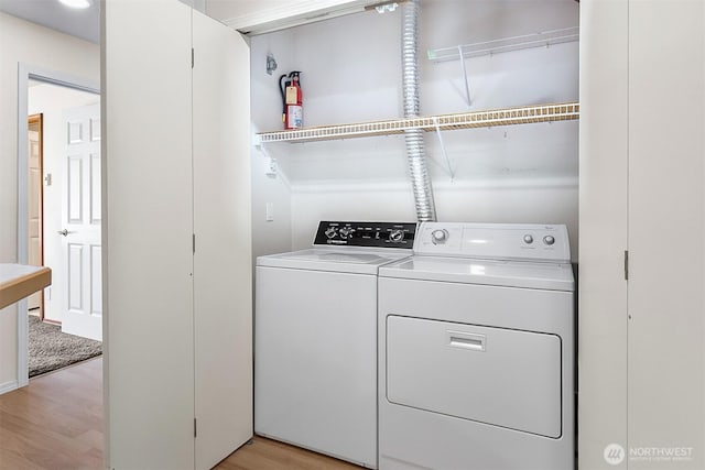 clothes washing area featuring laundry area, washer and clothes dryer, and light wood-style floors
