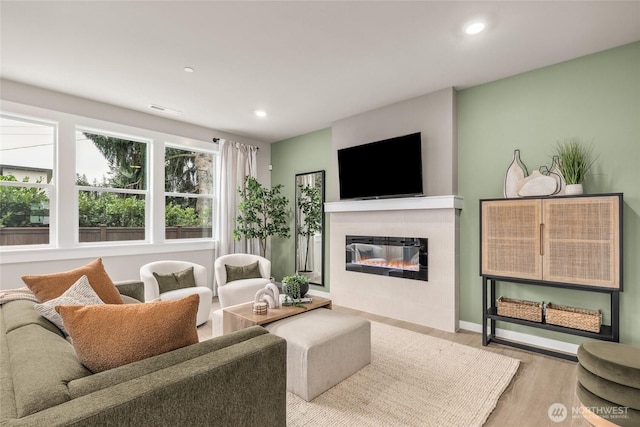 living area with recessed lighting, wood finished floors, visible vents, and a fireplace