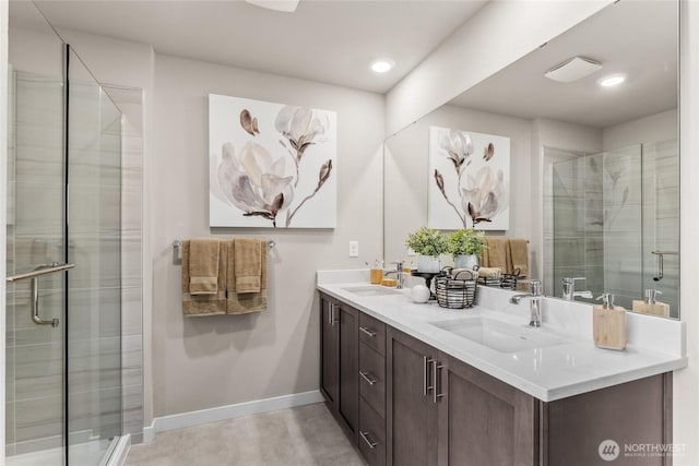 full bathroom featuring double vanity, baseboards, a shower stall, and a sink