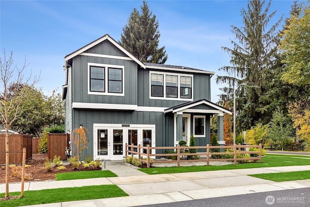view of front of house with a fenced front yard, board and batten siding, and french doors