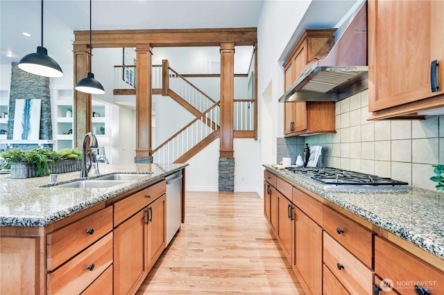 6722 Azalea Way SE, Snoqualmie, WA 98065 - kitchen featuring a sink, wall chimney range hood, light wood-style floors, appliances with stainless steel finishes, and ornate columns