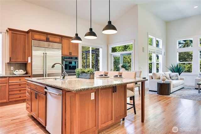 6722 Azalea Way SE, Snoqualmie, WA 98065 - kitchen with appliances with stainless steel finishes, a sink, light wood-type flooring, a towering ceiling, and light stone counters