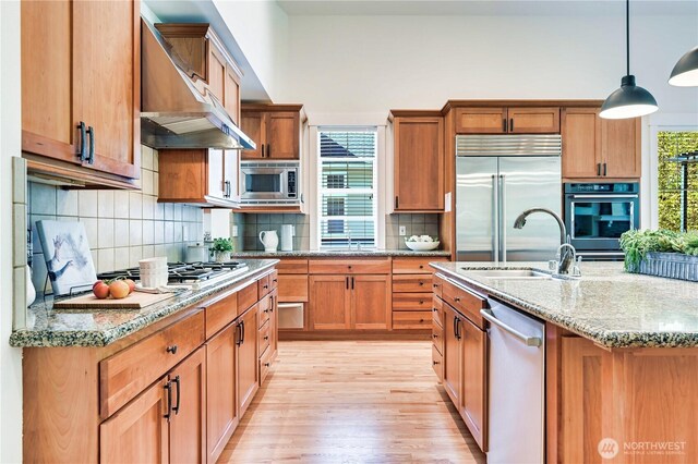 6722 Azalea Way SE, Snoqualmie, WA 98065 - kitchen featuring built in appliances, wall chimney range hood, light wood-style floors, a sink, and decorative backsplash