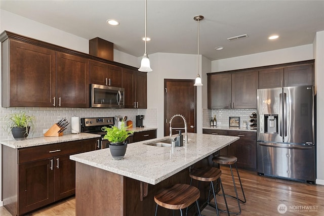 9957 Justman St SE, Yelm, WA 98597 - kitchen featuring visible vents, wood finished floors, dark brown cabinets, a sink, and stainless steel appliances