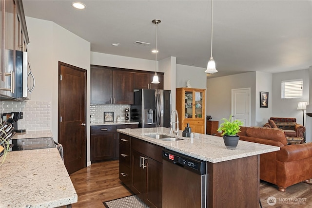 9957 Justman St SE, Yelm, WA 98597 - kitchen with dark brown cabinets, appliances with stainless steel finishes, a sink, open floor plan, and backsplash