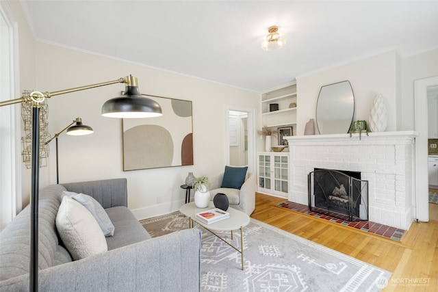 living room with ornamental molding, built in features, a brick fireplace, and wood finished floors
