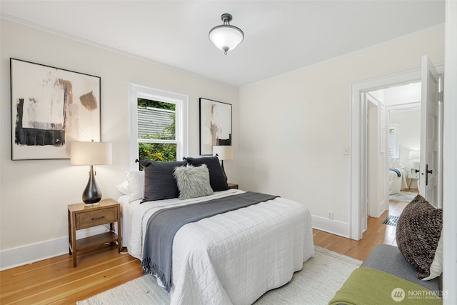 bedroom with light wood-style floors, ornamental molding, and baseboards