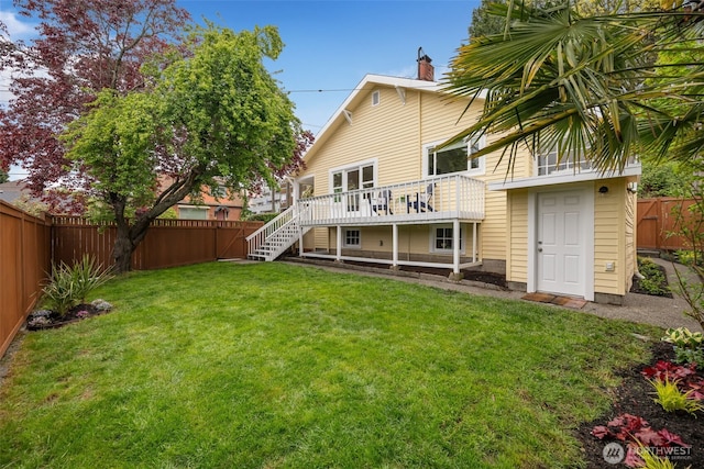 rear view of house featuring a deck, a fenced backyard, a chimney, a lawn, and stairway