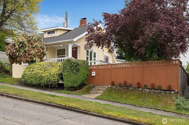 view of front of house with a porch, fence, and a chimney
