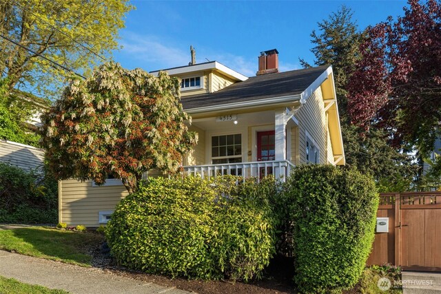 view of front of property with a porch, a chimney, and a gate