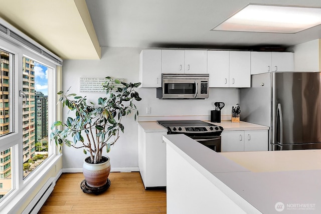 kitchen with light countertops, light wood-style flooring, stainless steel appliances, baseboards, and a baseboard heating unit