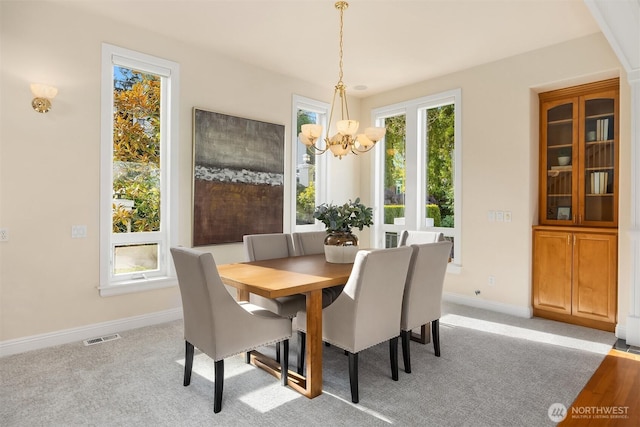 dining space with a healthy amount of sunlight, baseboards, visible vents, and a chandelier