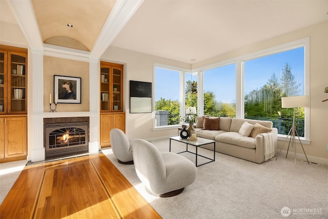 living room with baseboards, a fireplace with flush hearth, a healthy amount of sunlight, and built in shelves