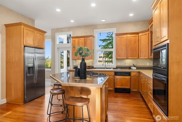 kitchen with plenty of natural light, a sink, black appliances, and wood finished floors