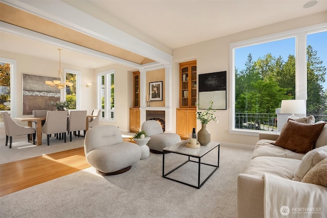 carpeted living room featuring baseboards, plenty of natural light, and a notable chandelier