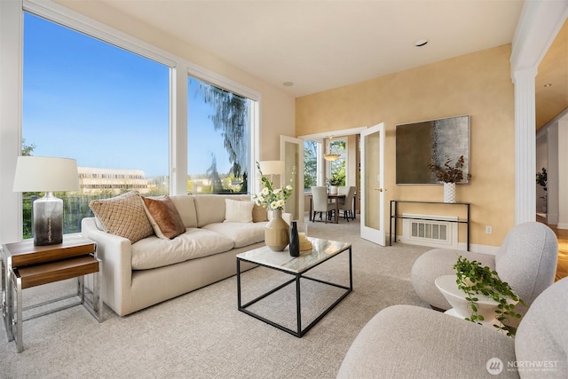 living area featuring baseboards, decorative columns, and carpet floors