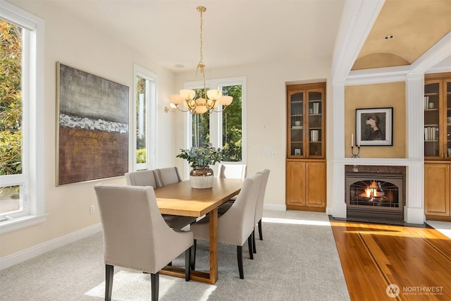 dining room with baseboards, a notable chandelier, and a fireplace