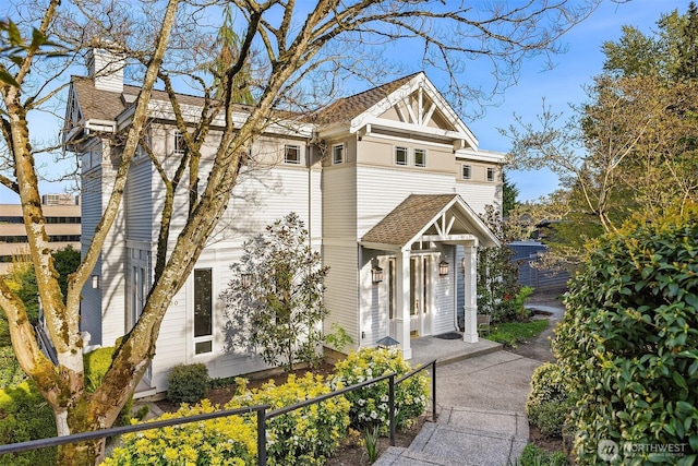 view of front of house with fence, a shingled roof, and a chimney