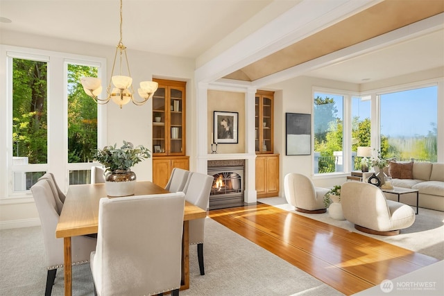 dining room featuring a high end fireplace, beamed ceiling, a chandelier, and a healthy amount of sunlight