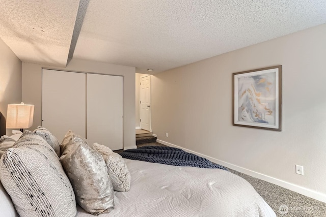 bedroom with a closet, baseboards, carpet flooring, and a textured ceiling