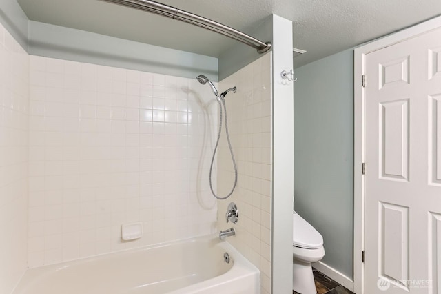 bathroom featuring shower / bathtub combination, toilet, and a textured ceiling