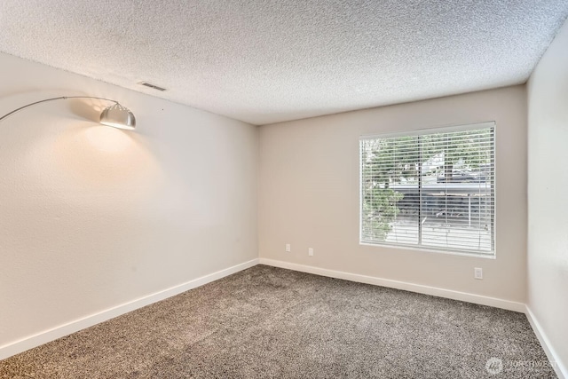 carpeted spare room with baseboards, a textured ceiling, and visible vents