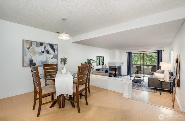 3518 109th Pl NE Unit 223, Bellevue, WA 98004 - dining space with light wood-style flooring, a multi sided fireplace, and a textured ceiling