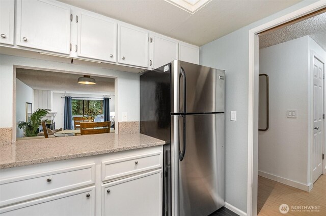 3518 109th Pl NE Unit 223, Bellevue, WA 98004 - kitchen with freestanding refrigerator, white cabinets, light wood finished floors, and light stone countertops