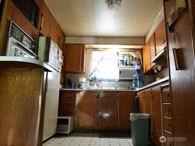 2522 Chesney Rd E, Tacoma, WA 98445 - kitchen with light countertops, light floors, brown cabinetry, and oven